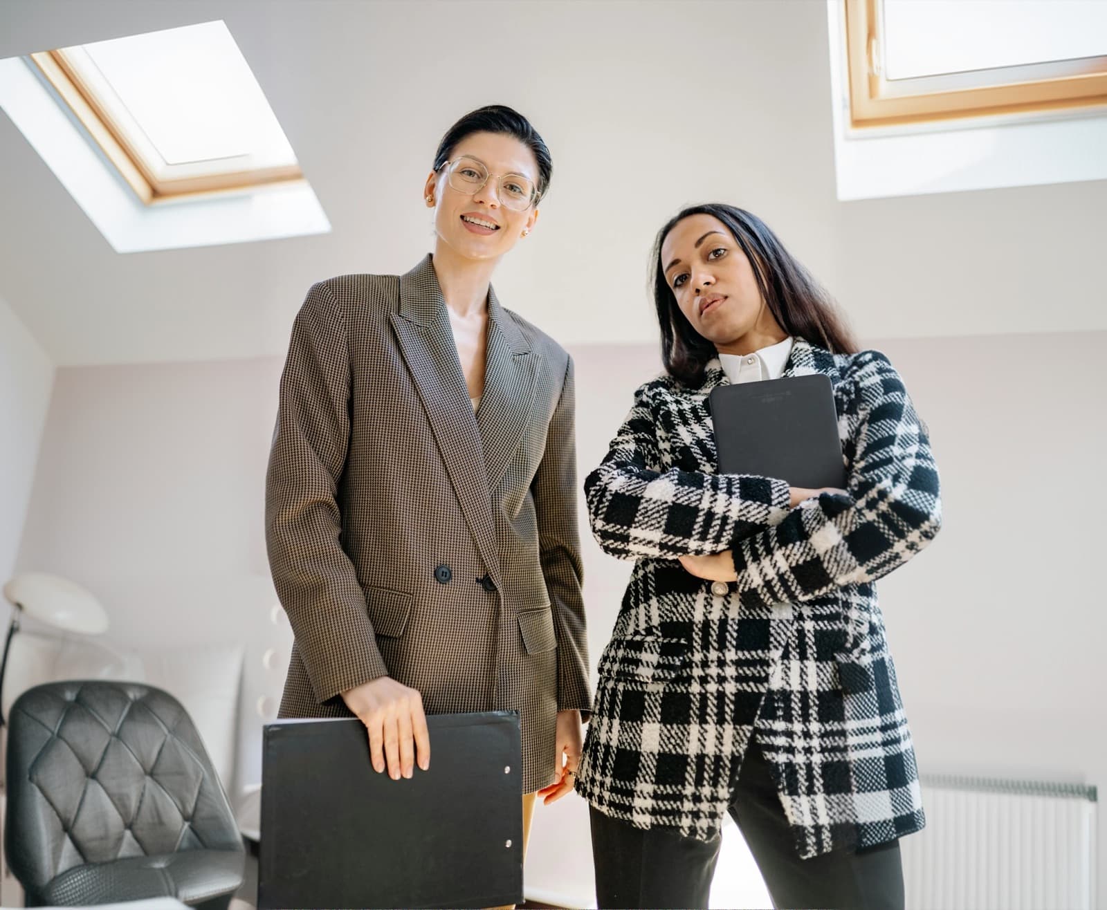 Two professional mentors standing together in a modern workspace